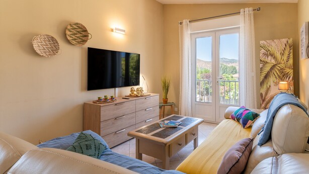 Een moderne woonkamer met een bank, een salontafel, een televisie en een balkon met uitzicht.