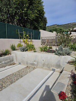 A landscaped garden with a concrete pathway, various plants, and a wooden fence.