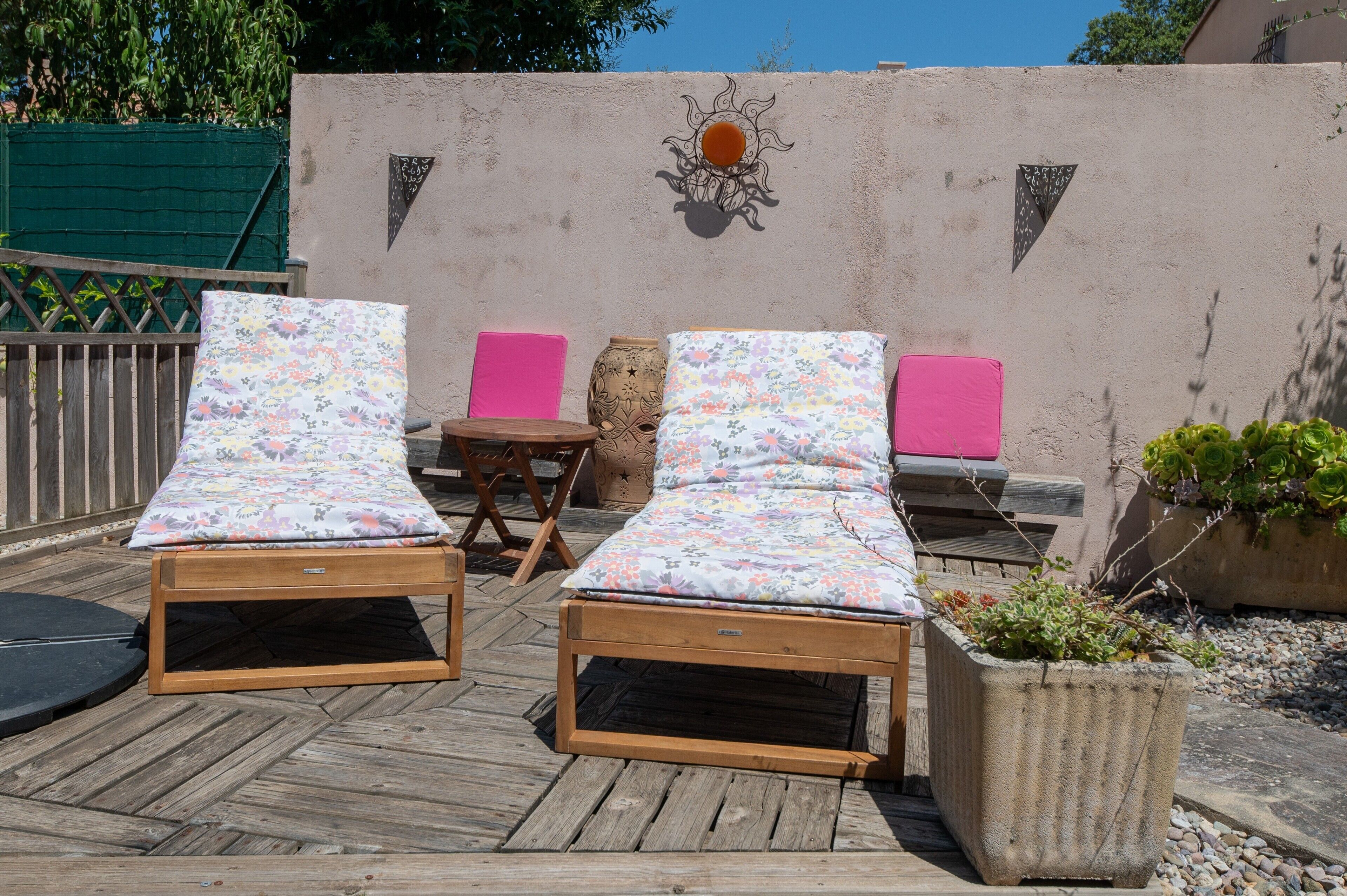 Un terrazza in legno con due poltrone relax e un tavolino.