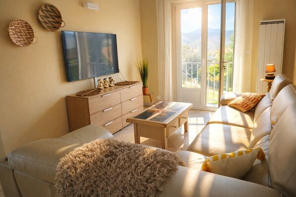 A living room with a sofa, a coffee table, a TV, and a sliding glass door leading to a balcony.