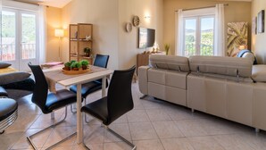Een moderne woonkamer met een bank, eettafel, stoelen en een televisie.