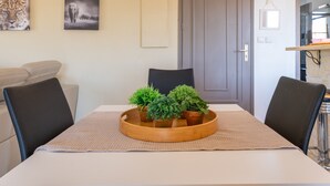 Een eettafel met een dienblad vol potplanten, een bank en een deur op de achtergrond.