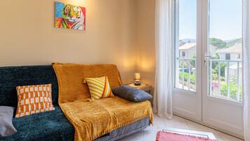 A room with a dark green sofa, a mustard-colored throw blanket, and a painting of a tiger on the wall.