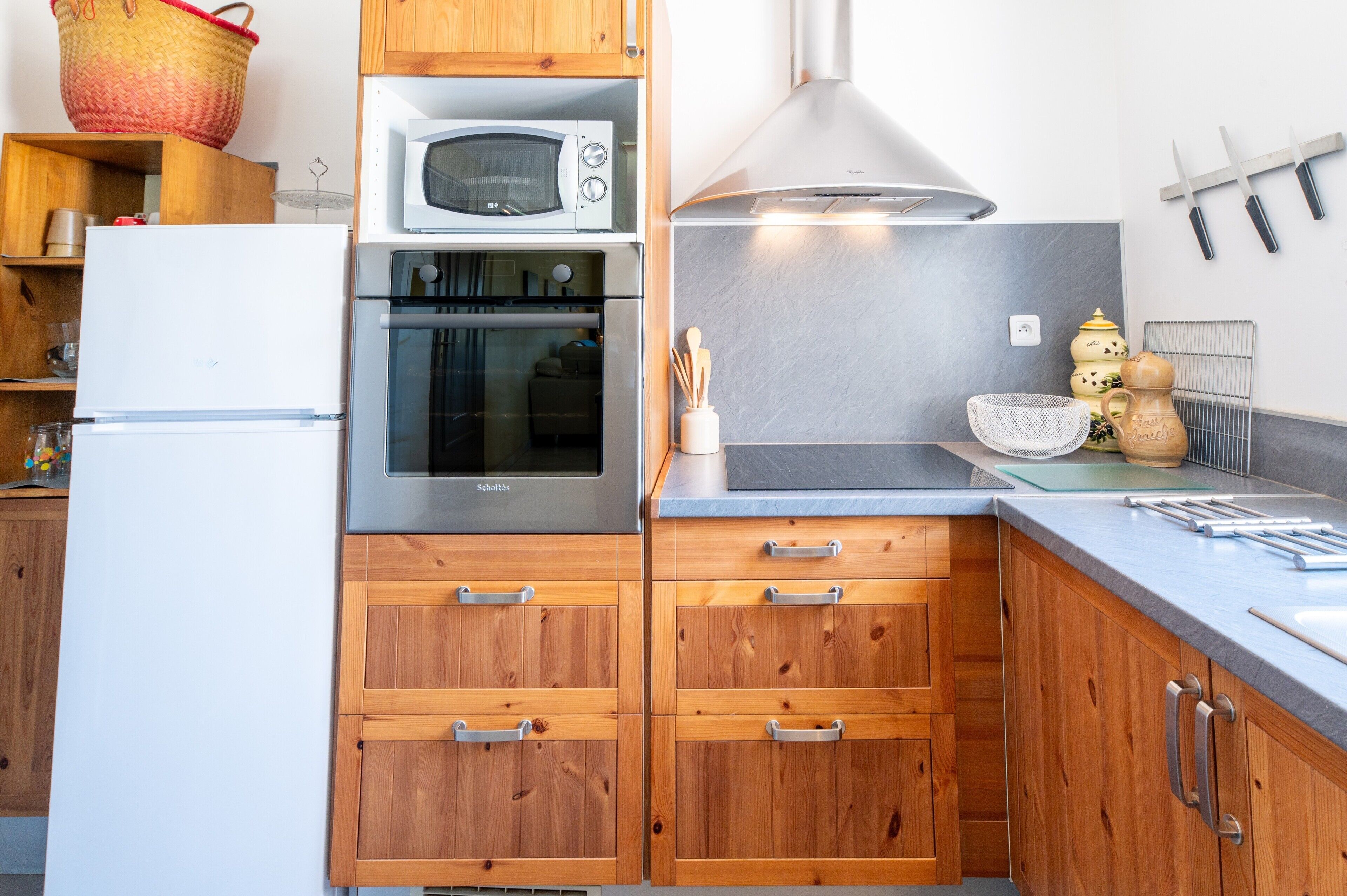 A kitchen with wooden cabinets, a white refrigerator, a built-in oven, a microwave, and a stainless steel range hood.