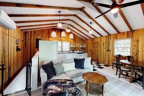 A cozy cabin interior with a wooden interior, a sofa, a dining table, and a kitchen area. - Nantahala Lake Hideout (Topton)