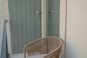 Uma cadeira de vime colocada em frente a um edifício com porta verde.