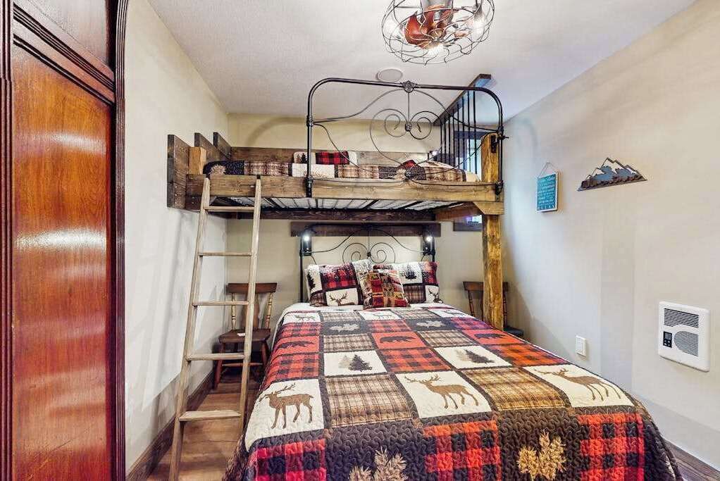 Ein Etagenbett mit einer Stehle, eine Decke mit Tiermotiven und eine rustikale Holzleiter.