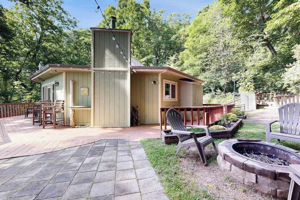 Een houten vakantiehuis met terras, buitenmeubels en een vuurkuil.