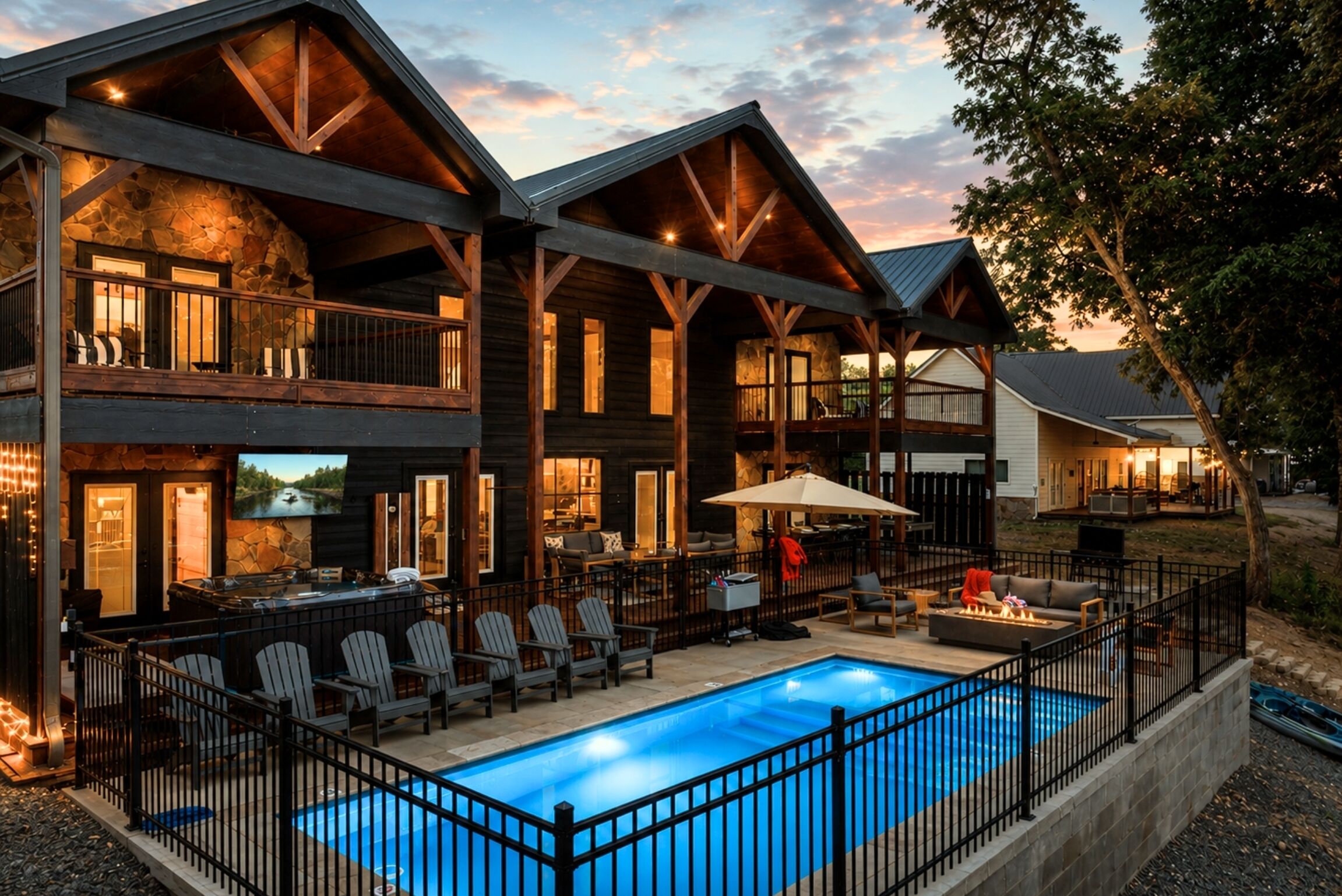 A two-story lodge with a swimming pool, outdoor seating, and a stone fireplace.