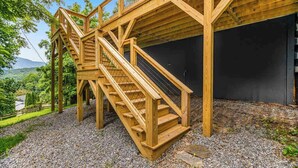 Eine Holztreppe führt zu einem Gebäude im modernen Design, umgeben von Kies und Grünflächen.