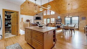 A spacious kitchen with wooden cabinets, a dining area with a table and chairs, and a large island. - The Glens of Iron Duff (Waynesville)