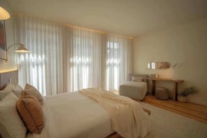Quarto com cama, mesa de cabeceira, abajur e cortinas.