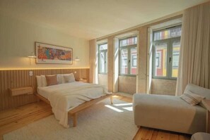Quarto com cama, sofá, janela e pintura na parede.