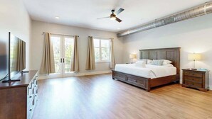 Ein geräumiges Schlafzimmer mit einem großen Bett, einem Deckenventilator, einem Fernseher und einer Holzkommode.