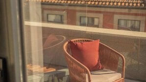 Une chaise en osier avec un coussin sur un balcon.