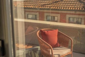 A wicker chair with a cushion on a balcony. - 3. Deluxe Suite (River and City View) (Porto)