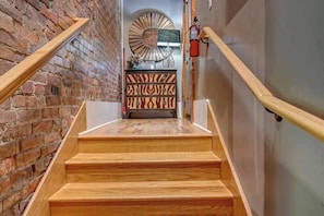 A wooden staircase with a brick wall on one side and a decorative wall on the other. - #102 - The Lofts at Church Street (Asheville)