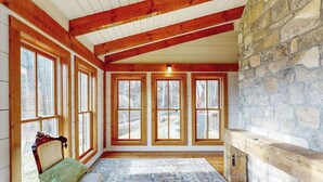 Una habitación con ventanas amplias, una pared de piedra y un banco.