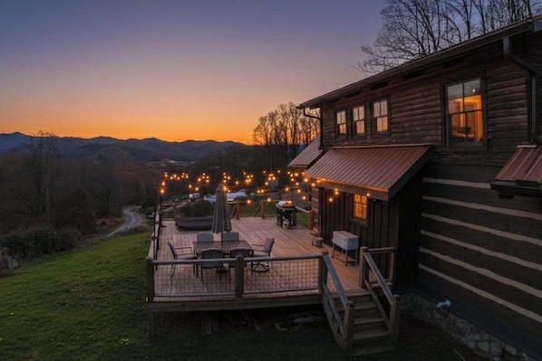 Eine Holzhütte mit einer Terrasse, Gartenmöbeln und Lichterketten.