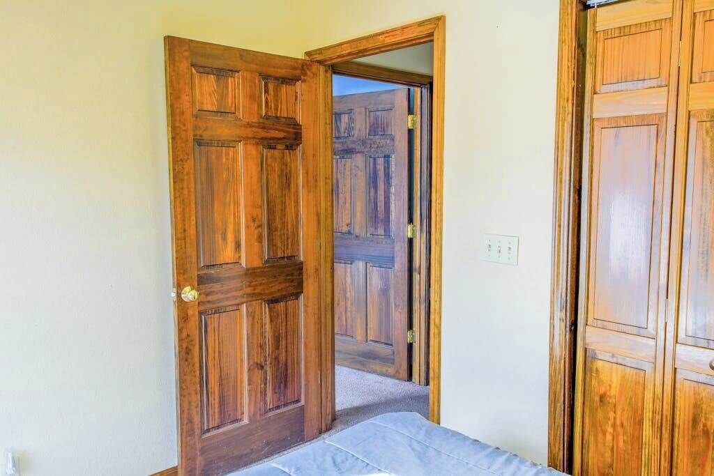 A room with wooden doors, a bed, and a visible door leading to another room.