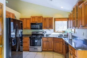 A kitchen with wooden cabinets, a refrigerator, a microwave, an oven, and a sink.
