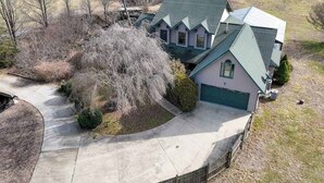 A two-story house with a green roof, a driveway, and a fenced yard. - Meadow Creek Manor (Whittier)