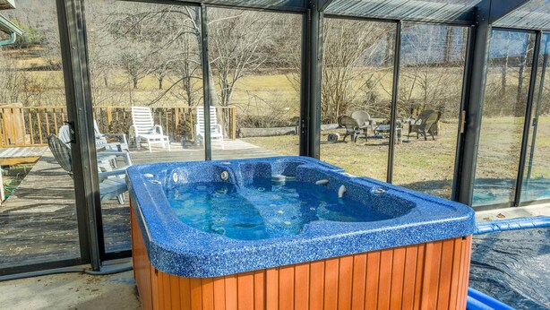 A hot tub with a wooden exterior and a blue interior, surrounded by a glass enclosure. - Meadow Creek Manor (Whittier)