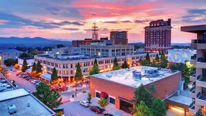 A downtown area with a mix of historic and modern buildings, a parking lot, and a clear sky. - Modern art-deco condo with balcony, central AC, & washer/dryer - dogs OK (Asheville)
