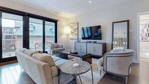 A modern living room with a sofa, a coffee table, a TV, and a cabinet. - Modern art-deco condo with balcony, central AC, & washer/dryer - dogs OK (Asheville)