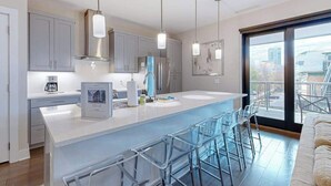 A modern kitchen with a central island, bar stools, and a large window offering a city view. - Modern art-deco condo with balcony, central AC, & washer/dryer - dogs OK (Asheville)