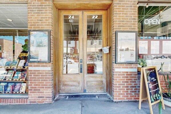 A storefront with a brick facade, numbered doors, and a display of books.