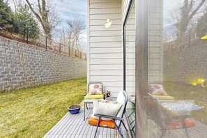 Eine Terrasse mit Gartenmöbeln, eine Steinmauer und ein Gebäude mit einem Fenster.