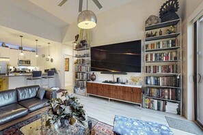 Ein modernes Wohnzimmer mit Sofa, Couchtisch, Bücherregal und einem Flachbildfernseher.