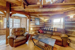 Ein rustikales Holzhaus-Interieur mit Ledersofa, Couchtisch und Holzwänden.