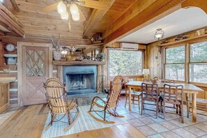 Ein rustikales Interieur mit Kamin, Holzmöbeln und großen Fenstern.
