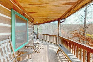 Eine Holzterrasse mit Bänken und einem Geländer, mit Blick auf ein bewaldetes Gebiet.
