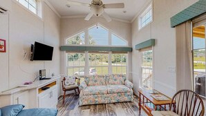 A spacious room with a ceiling fan, a sofa, a wooden table, and a TV. - Pet Friendly Tiny home in Great Location with Grill and Covered Porch (Hendersonville)