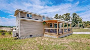 A single-story house with a covered porch, a small attached garage, and a grassy yard. - Pet Friendly Tiny home in Great Location with Grill and Covered Porch (Hendersonville)