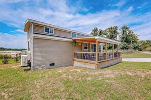 A single-story house with a covered porch, a small attached garage, and a grassy yard.
