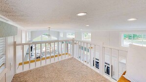 A spacious room with a high ceiling, large windows, and a view of the outdoors. - Pet Friendly Tiny home in Great Location with Grill and Covered Porch (Hendersonville)