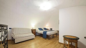 Une pièce avec un canapé, un lit, une petite table et un arbre à chat.