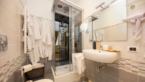 Une salle de bain avec une douche à parois de verre, un lavabo avec un miroir, un sèche-cheveux et un porte-serviettes.
