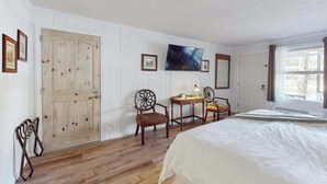 A bedroom with a bed, a desk, two chairs, a television, and a large window. - Dog-friendly lakefront condo with pool, canoes, & WiFi - in a perfect location (Flat Rock)