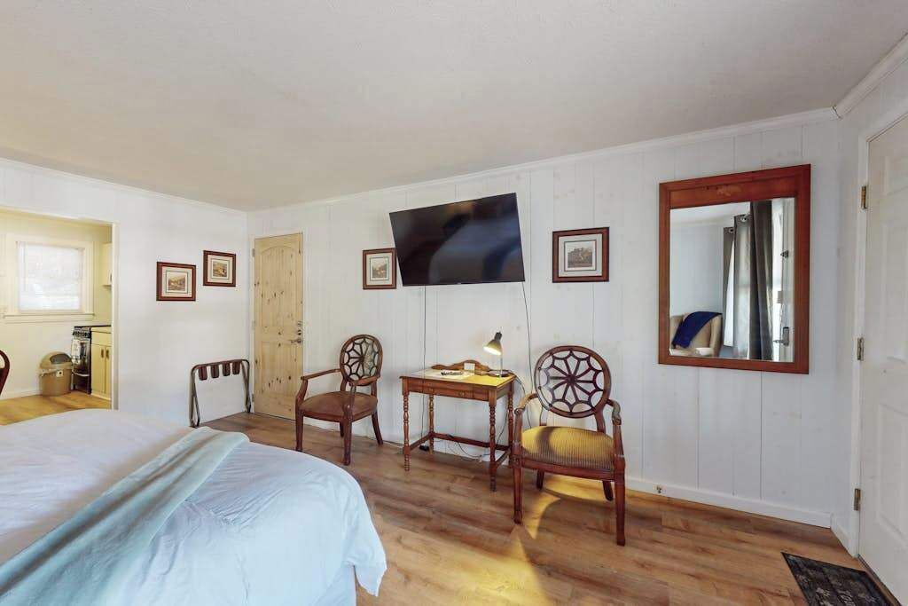 A room with a bed, a desk, a chair, a television, and a mirror.