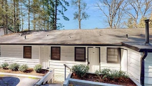 A single-story building with a sloped roof, multiple windows, and a small porch area. - Dog-friendly lakefront condo with pool, canoes, & WiFi - in a perfect location (Flat Rock)