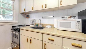 A kitchen with white cabinets, a stove, a sink, and a microwave. - Dog-friendly lakefront condo with pool, canoes, & WiFi - in a perfect location (Flat Rock)