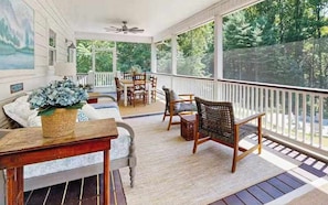 Eine überdachte Veranda mit Esstisch, Stühlen und Deckenventilator.