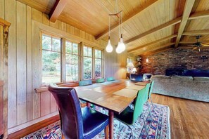 Ein Zimmer mit Holzwänden, einem großen Tisch, Stühlen und einer Couch.