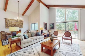 A spacious living room with a high ceiling, a large window, and a balcony. - Idyllic Mountain Escape | Grill, Outdoor Lounge | 4 Mins to Flat Rock Village (Hendersonville)