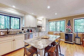 A kitchen with a granite island, white cabinets, and an American flag. - Idyllic Mountain Escape | Grill, Outdoor Lounge | 4 Mins to Flat Rock Village (Hendersonville)